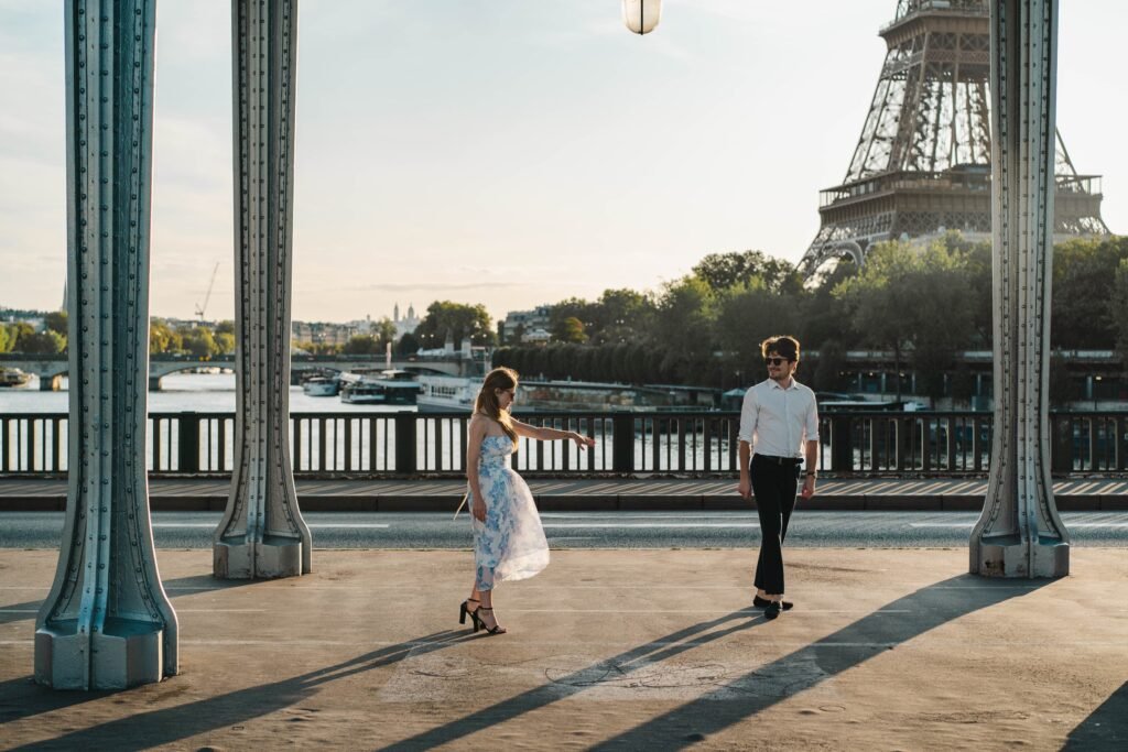 Couple walking near the Eiffel Tower in Paris A man and woman walking on a bridge with the Eiffel Tower in the background in Paris