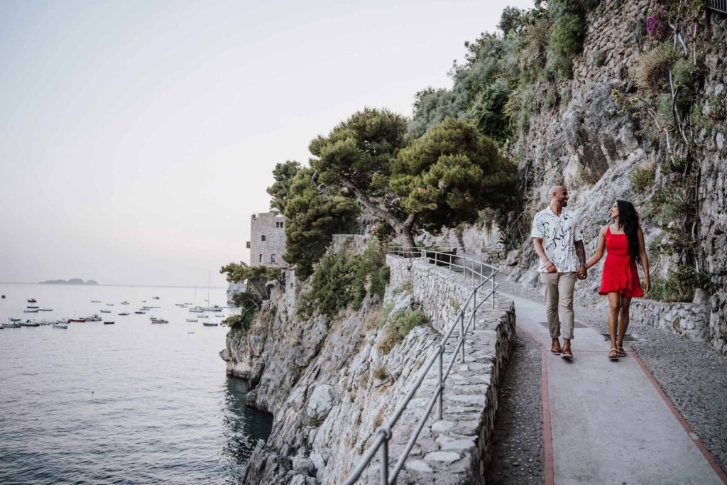 amalfi coast photographer mimmo-10 Couple holding hands while walking along a scenic coastal path in Positano above the sea