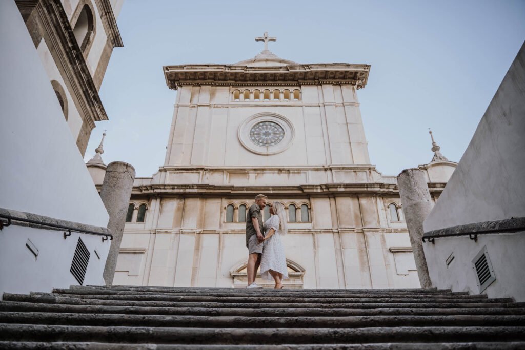 Couple standing on stone steps in Positano A couple standing together on large stone steps in Positano, framed by historic buildings.