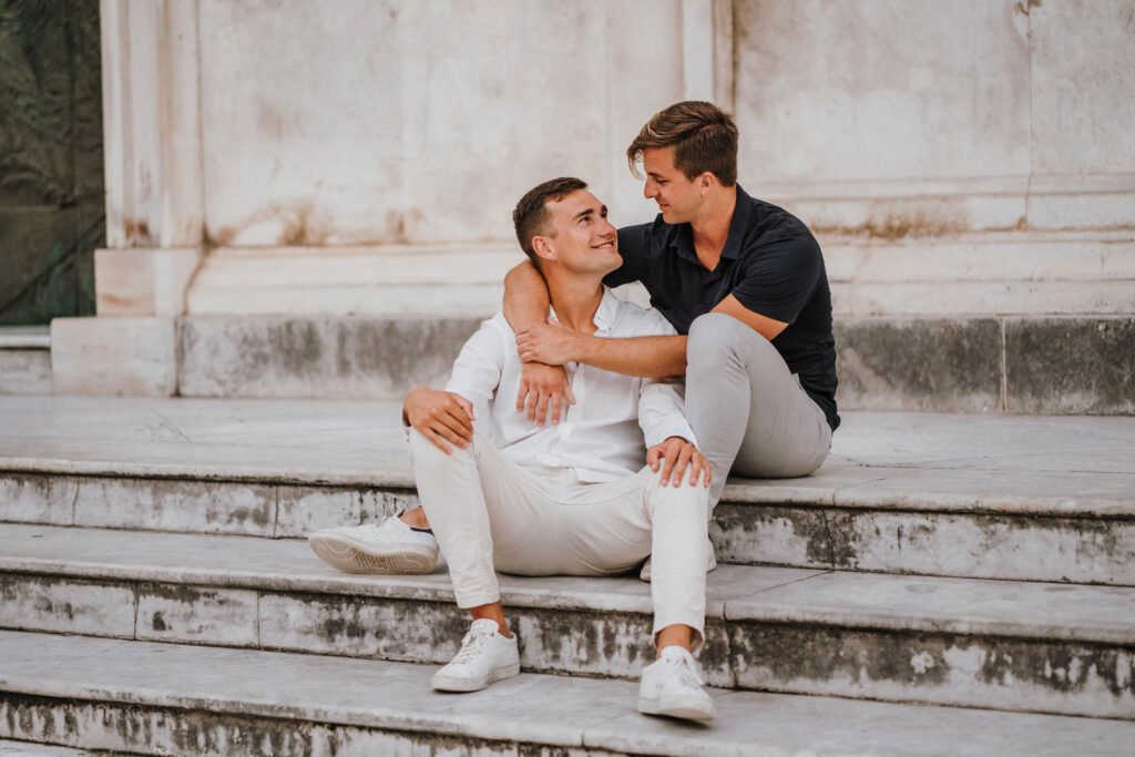 Two young men sitting together on stone steps Two young men sitting together on stone steps and smiling at each other