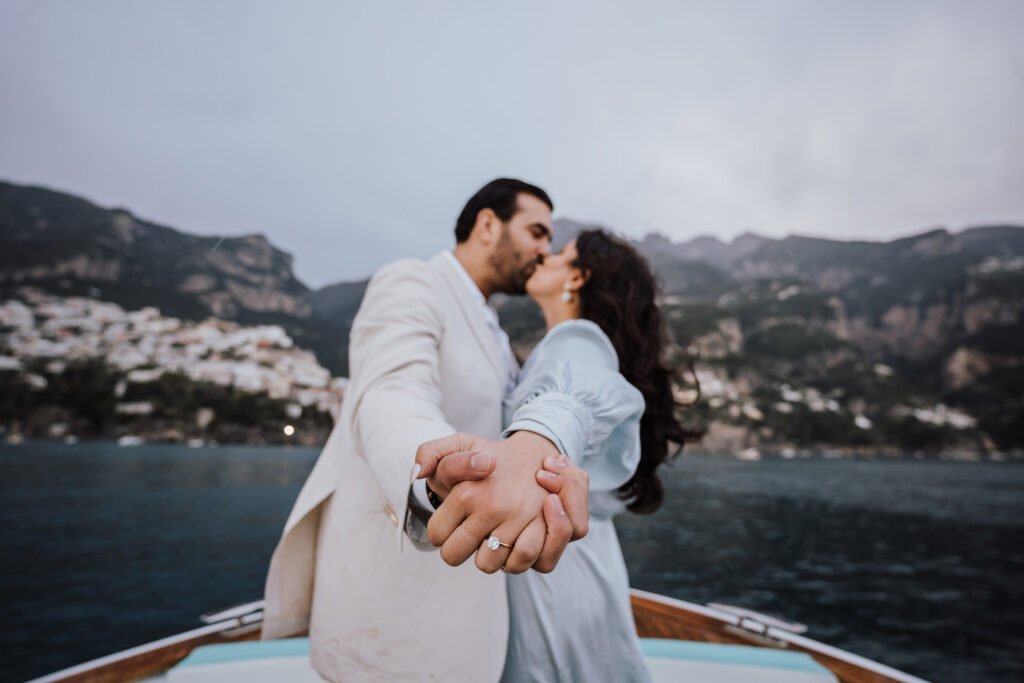 Couple kissing on a boat in Positano Couple holding hands and kissing on a boat with Positano coastline in the background