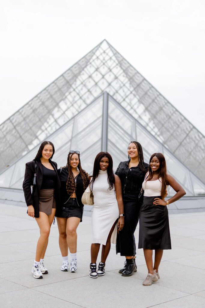 Five women posing in front of the Louvre Pyramid in Paris Five women posing together in front of the glass pyramid at the Louvre in Paris