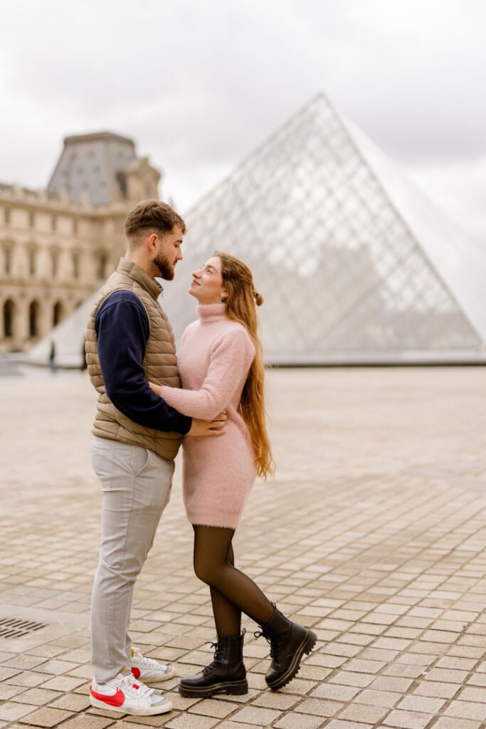 Couple embracing in front of the Louvre Pyramid in Paris A couple hugging and looking at each other near the Louvre Pyramid in Paris