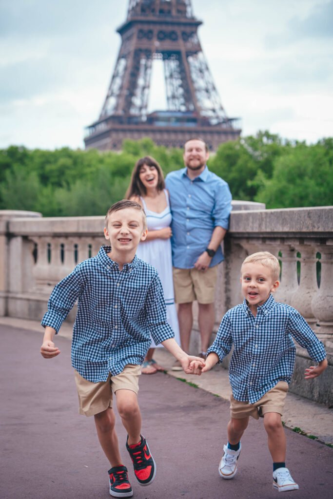 Family running together with the Eiffel Tower in Paris Two young boys running in front of their parents with the Eiffel Tower in Paris behind them