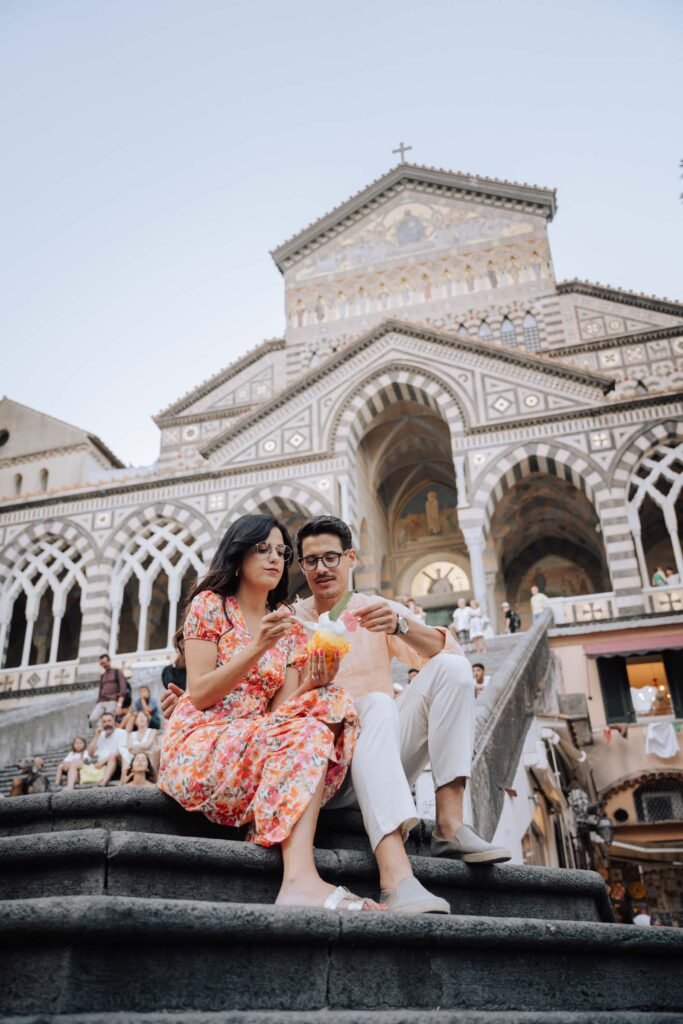 Couple eating dessert on steps in Amalfi Couple sitting on stone steps sharing dessert in front of Amalfi Cathedral