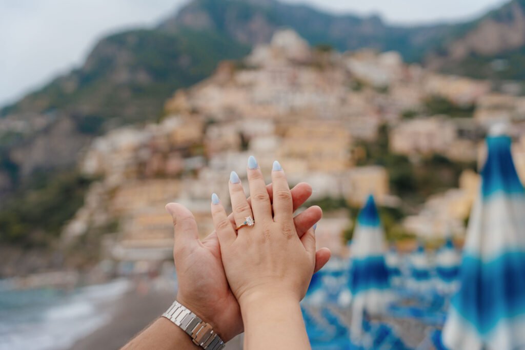 Engagement ring with Positano coastline view Close-up of hands holding with a diamond engagement ring, overlooking Positano coastline