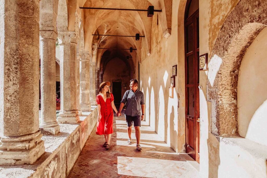 Couple walking hand in hand along historic stone corridor in Ravello Couple walking hand in hand along a historic vaulted stone corridor with columns in Ravello