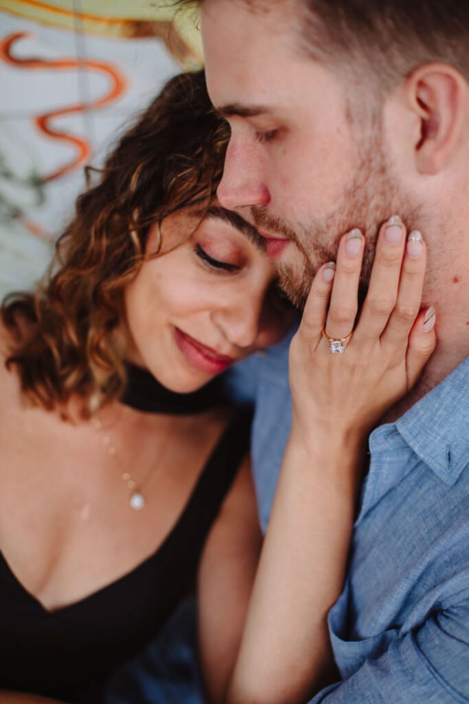 Close-up of woman holding man face with engagement ring Close-up of a woman gently touching a man's face, displaying a diamond engagement ring on her finger